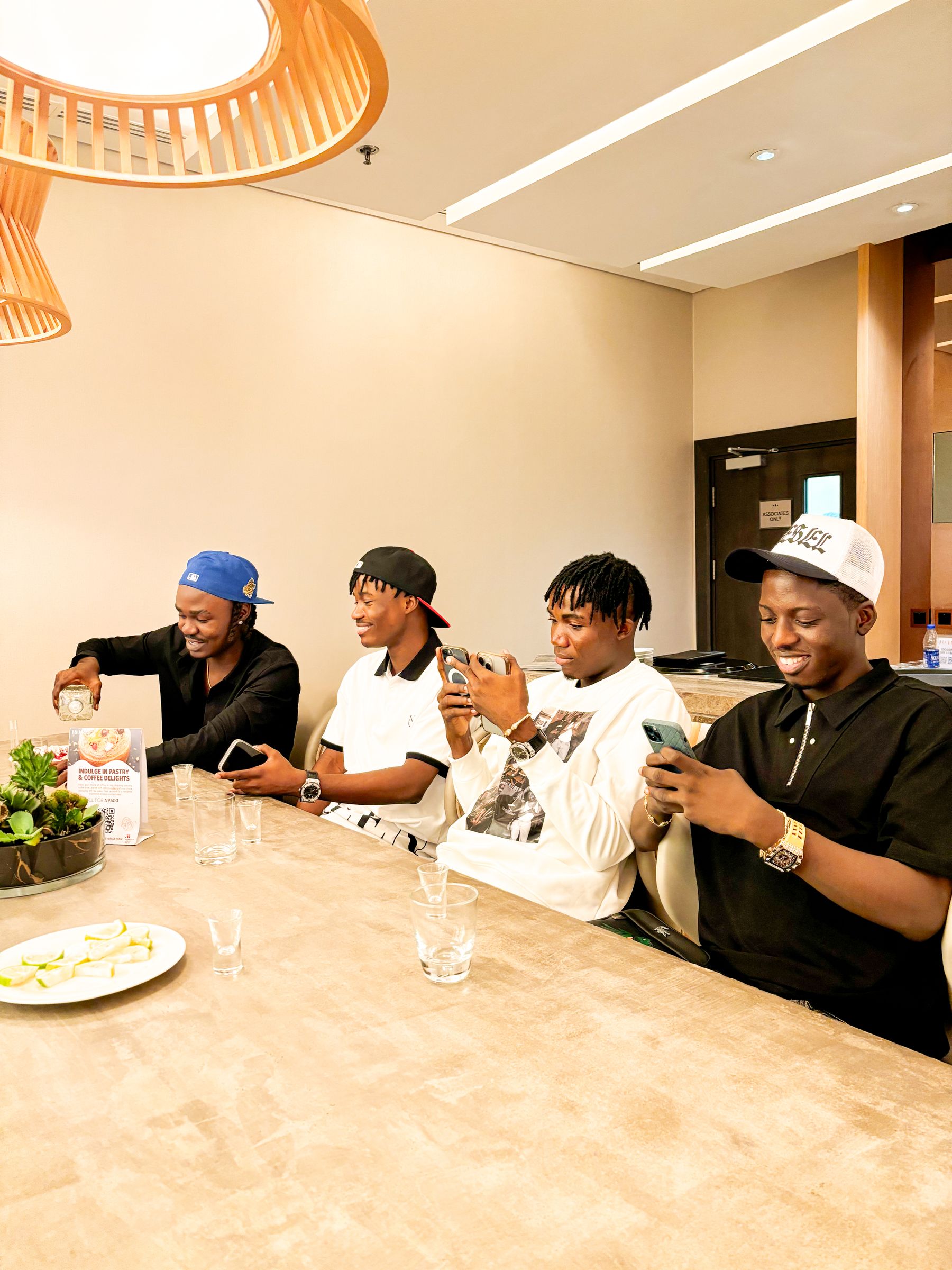 African friends seated together using their phones during a shared meal